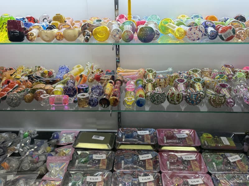 Display case of colorful glass handpipes, chillums and rolling trays at Lionz