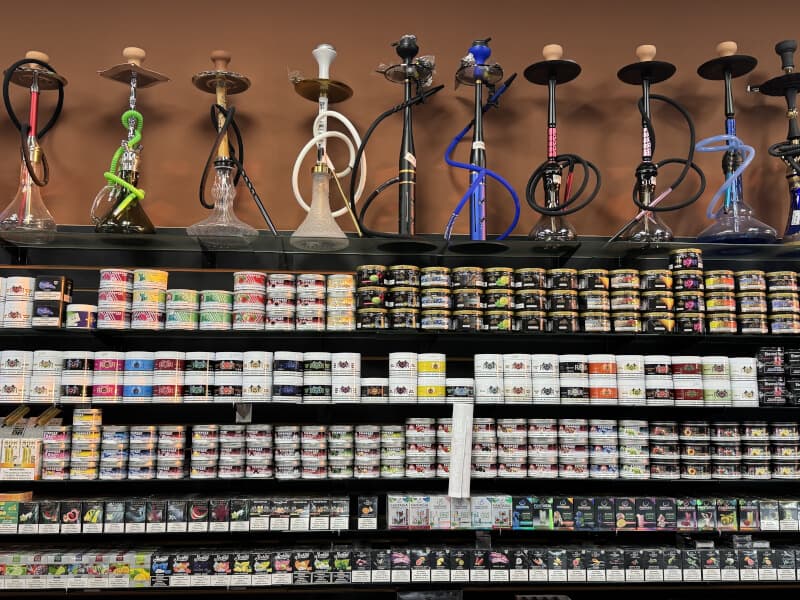 Hookah pipes displayed above shelves of flavored shisha tobacco at Lionz